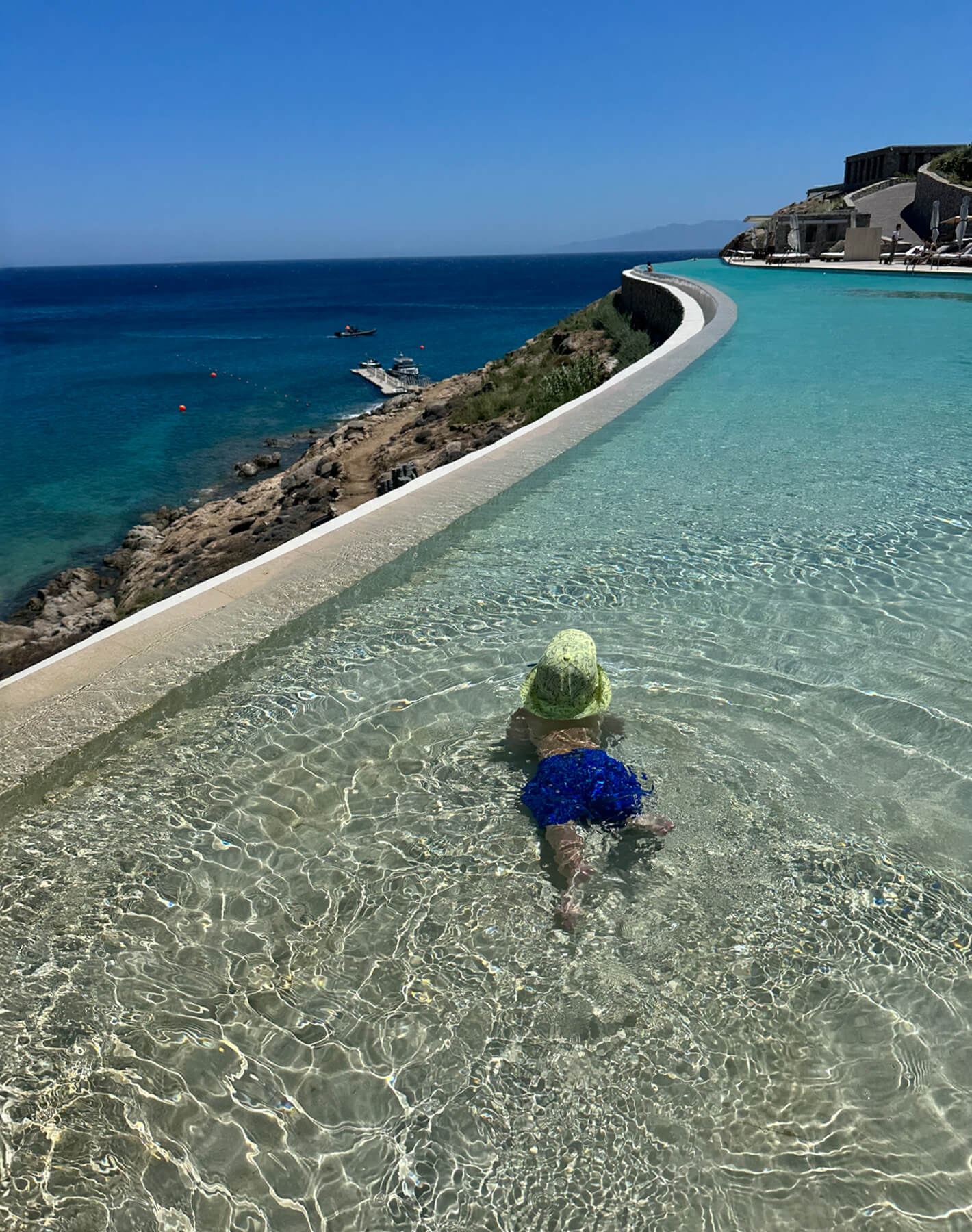 Toddler enjoying a splash at the shallow end of Cali's infinity pool. Beautiful sunny day in Mykonos!